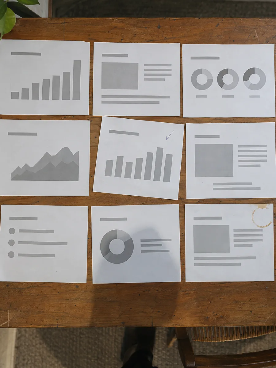 Printed pitch deck slides laid out in a grid on a table and reviewed one by one