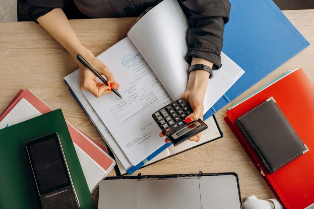 An accountant reviewing paper records with a calculator before entering or checking accounting data